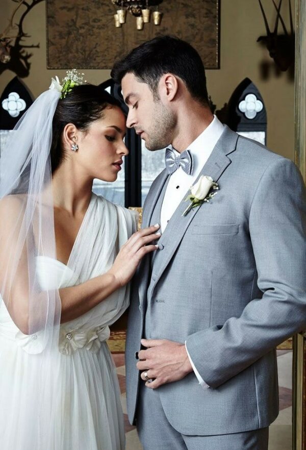 A bride and groom embrace, the groom is wearing the Infinity Notch rental tuxedo package.